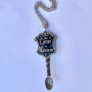 'Carpe Noctem' Tiny Festival Spoon Necklace with a shield shaped centerpiece charm that reads "Carpe Noctem" and matching black and silver wire wrapping on a small decorative silver spoon pendant base.