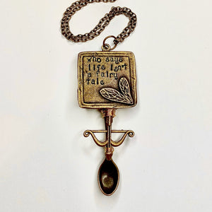 Custom Fairy Tale Jewelry Tiny Festival Spoon Pendant Necklace featuring a "Who says life isn't a fairy tale" quote main centerpiece charm with a matching bow and arrow charm wire wrapped to a large scoop size bronze spoon pendant base.